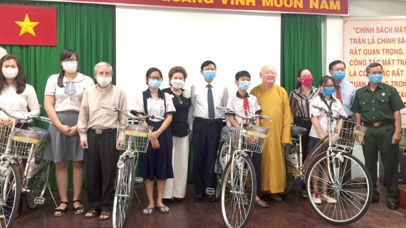 Chị Đặng Thị Minh Nguyệt (thứ tư, từ trái sang) tặng phương tiện đi học  cho học sinh, sinh viên hoàn cảnh khó khăn