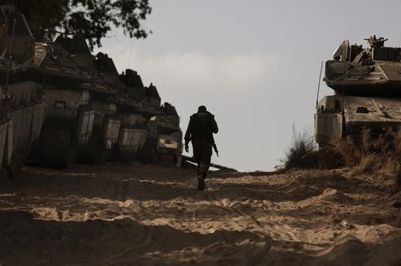Một binh sĩ Israel đi bộ dọc theo những chiếc xe tăng hạng nặng được triển khai tới gần Dải Gaza. Ảnh: AP