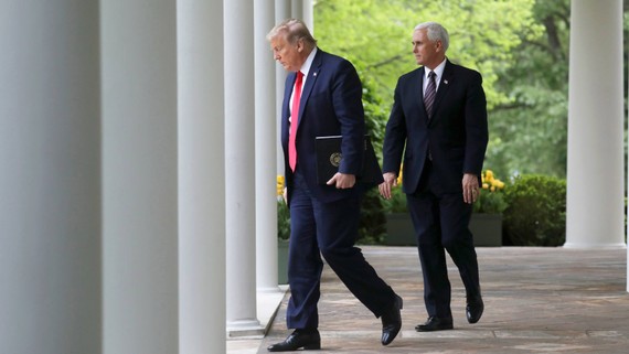 U.S. President Donald Trump walks down the West Wing colonnade from the Oval Office with Vice President Mike Pence as they arrive to address the daily coronavirus task force briefing in the Rose Garden at the White House on April 14.   © Reuters