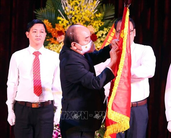 Chủ tịch nước Nguyễn Xuân Phúc gắn Huân chương Lao động hạng Nhất lên lá cờ truyền thống của Trường Đại học Sư phạm Hà Nội. Ảnh: TTXVN