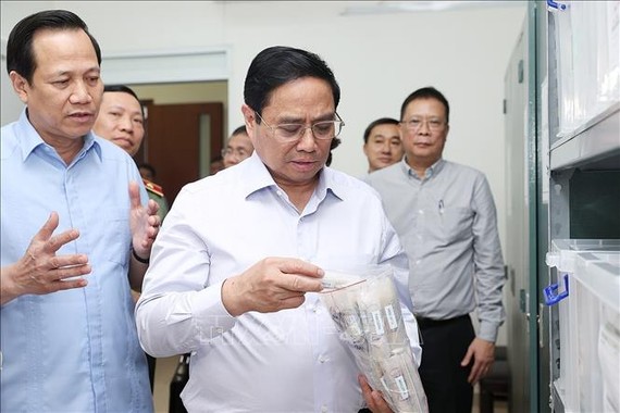 Thủ tướng Phạm Minh Chính xem quy trình bảo quản mẫu hài cốt tại Trung tâm Giám định ADN hài cốt liệt sĩ. Ảnh: TTXVN