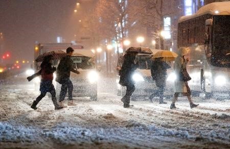 Pedestrians cross the street in the snow, in front of JR Yotsuya Station, in Tokyo, on Monday. - KYODO