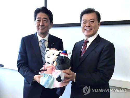 The file photo, taken Sept. 7, 2017, shows South Korean President Moon Jae-in (R) offering the mascots of the 2018 PyeongChang Winter Olympic Games to Japanese Prime Minister Shinzo Abe before the start of their bilateral summit on the sidelines of a regi