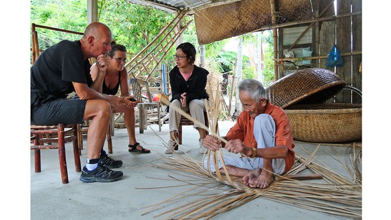 Ông Vũ Văn Khá (làng Kim Bồng, xã Cẩm Kim, TP Hội An) biểu diễn nghề đan thúng chai cho khách nước ngoài thưởng lãm