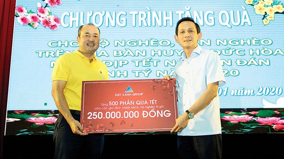Ông Lương Trí Thảo - Phó TGĐ Tập đoàn Đất Xanh (áo vàng, bên trái), đại diện Tập đoàn trao tặng 500 phần quà Tết đến chính quyền huyện Đức Hòa, tỉnh Long An