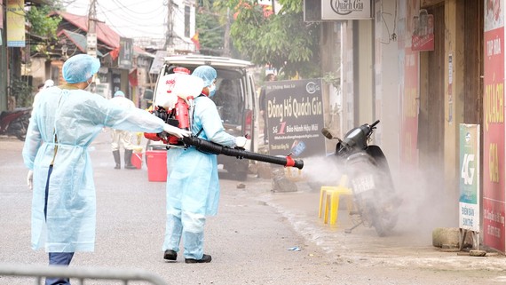 Lực lượng phun hóa chất tiêu độc khử trùng tại thôn Hạ Lôi. Ảnh: QUANG PHÚC