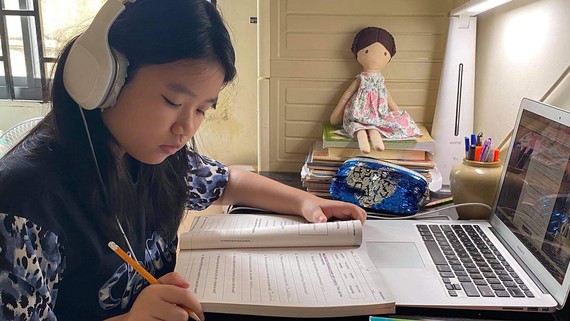 Em Khánh An (quận 8) đang tập trung theo bài học khi học trực tuyến tại nhà. Ảnh: HOÀNG HÙNG