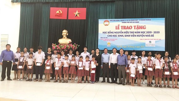 Ông Lê Văn Công, Kiểm Soát viên Công ty TNHH Một thành viên Xổ số kiến thiết TP Hồ Chí Minh cùng với lãnh đạo UBMTTQ TP, UBMTTQ huyện Nhà Bè và đơn vị Tài trợ chụp hình lưu niệm cùng với các em học sinh, sinh viên nhận học bổng