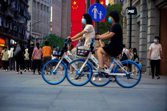 Phụ nữ đạp xe trên đường phố ở thành phố Thượng Hải, Trung Quốc, 10-5-2021. Ảnh: REUTERS