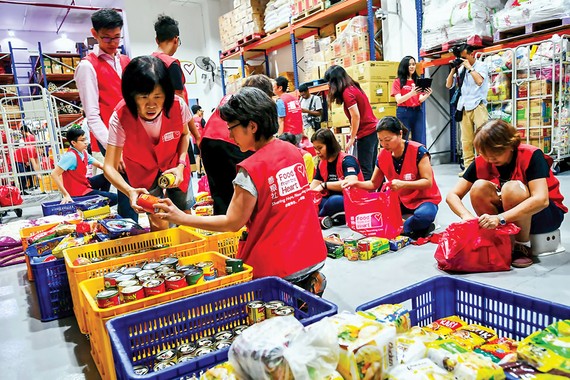 Các tình nguyện viên ở Singapore chuẩn bị thực phẩm giúp đỡ người gặp khó khăn vì dịch bệnh.