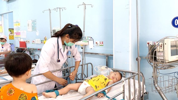 Bác sĩ  Bệnh viện Nhi đồng 1 đang thăm khám và điều trị cho bệnh nhi mắc tay chân miệng Ảnh:  MINH NAM