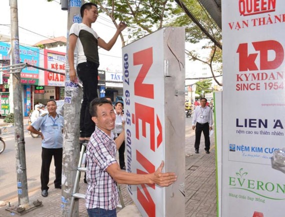 Người dân buôn bán trên đường Nguyễn Thị Thập, quận 7 tự nguyện tháo dỡ bảng quảng cáo lấn chiếm vỉa hè, vào đầu tháng 3-2017. Ảnh: Việt Dũng