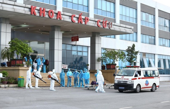 Lực lượng y tế phun thuốc khử khuẩn các công dân khi được đưa về Bệnh viện Nhiệt đới Trung ương cơ sở 2. (Ảnh: Minh Quyết/TTXVN)