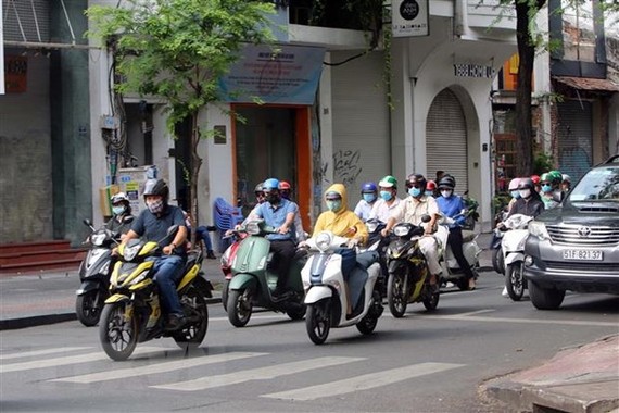 Người dân Thành phố Hồ Chí Minh thực hiện đeo khẩu trang phòng chống dịch COVID-19 khi tham gia giao thông. (Ảnh: Thanh Vũ/TTXVN)