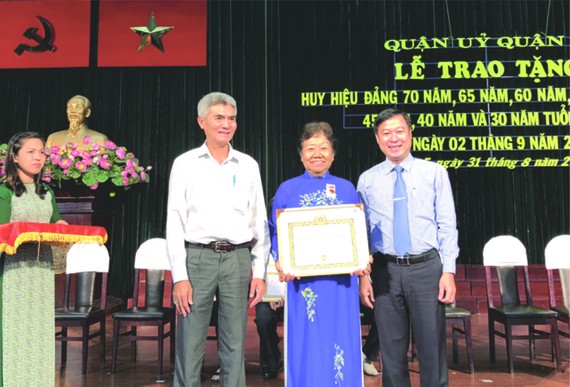 第五郡領導向華人黨員李金梅 頒贈50年黨齡紀念章。