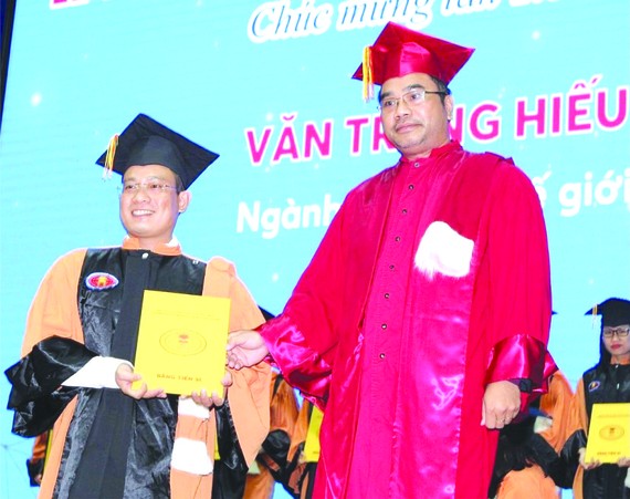 華人幹部文忠孝(左)接受頒發博士學位證書。
