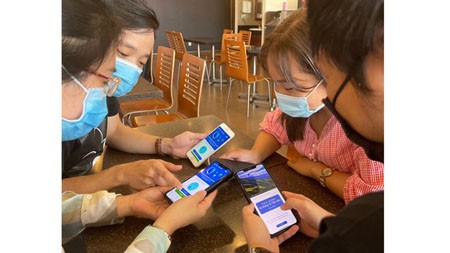 Young people are helping one another to install Bluezone app on their smart devices. (Photo: SGGP)