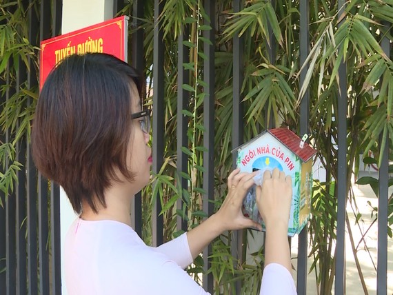 Cô giáo Nguyễn Thị Bích Trâm, trường Tiểu học Tây Hồ bỏ pin vào ngôi nhà được treo trước hàng rào của trường