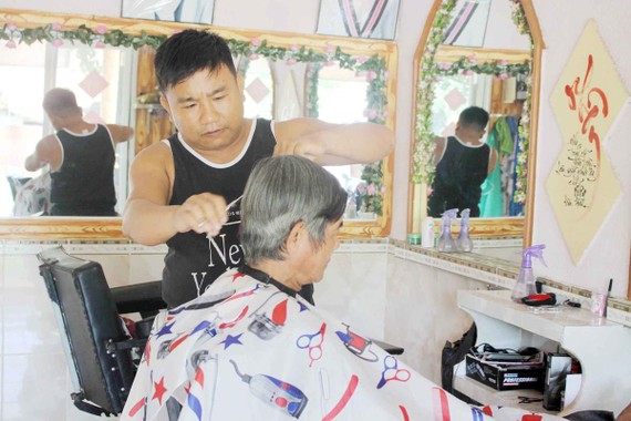 Anh Lê Minh Tân đang cắt tóc miễn phí cho một cụ già neo đơn