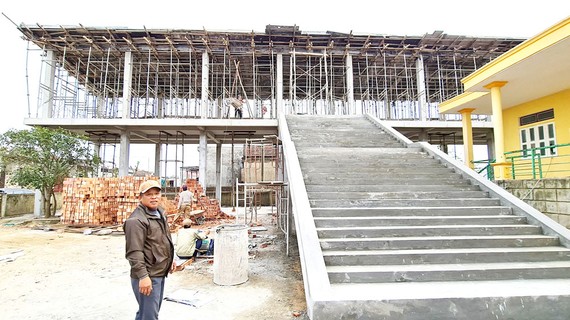 Trưởng thôn Nguyễn Trọng Trới bên căn nhà vượt lũ của thôn đang trong quá trình hoàn thiện. Ảnh: MINH PHONG