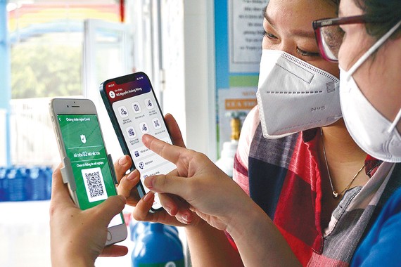 Chị Trần Thị Thanh Trang, huyện Bình Chánh, TPHCM  hướng dẫn thành viên gia đình sử dụng app sổ sức khỏe điện tử trên nền điện thoại thông minh. Ảnh: HOÀNG HÙNG