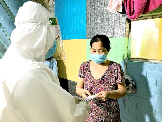 Nhân viên Trạm Y tế phường 11 (Bình Thạnh) thăm khám và cấp phát thuốc cho người bệnh tại nhà. Ảnh: BÙI TUẤN