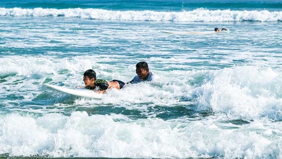 某小朋友在廣南省會安市安龐海上戴著浮袖學習衝浪。