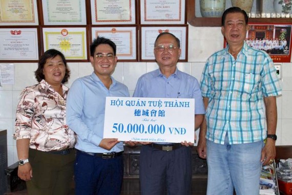 穗城會館理事長盧耀南(右二)和副理事長 林海泉(右一)向本報領導移交5000萬元贈款。