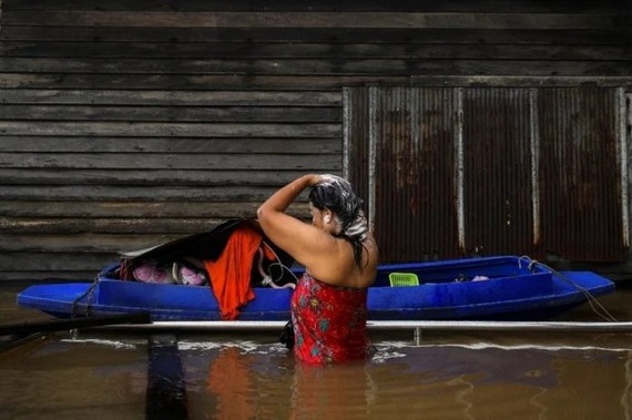 泰國曼谷郊區暖武里府的Tha-it清真寺附近強降雨後，一名婦女週二在被洪水淹沒的道路上洗澡。（圖：路透社）