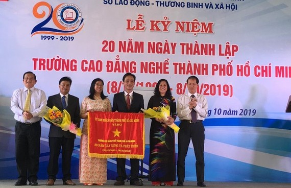 Ông Lê Minh Tấn, Giám đốc Sở LĐTB-XH TPHCM ( ngoài cùng bên trái) đại diện UBND TPHCM trao bức trướng của UBND TPHCM cho Ban Giám hiệu nhà trường