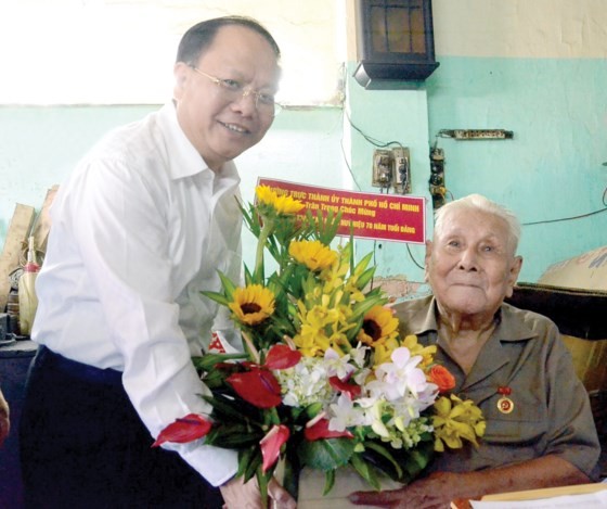 Deputy Standing Secretary of the Ho Chi Minh City Party Committee Tat Thanh Cang presents the 70-year Party membership badge to Party member Ly Toan Anh. (Photo: Sggp)