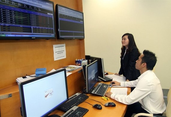 Specialists monitor a bidding session on the Hanoi Stock Exchange. (Photo: VNA)