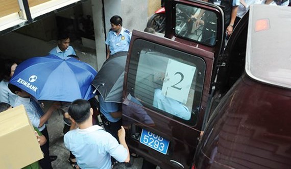 Officers from the Ministry of Public Security arrest two employees of Eximbank’s Ho Chi Minh City branch. (Photo: Sggp)