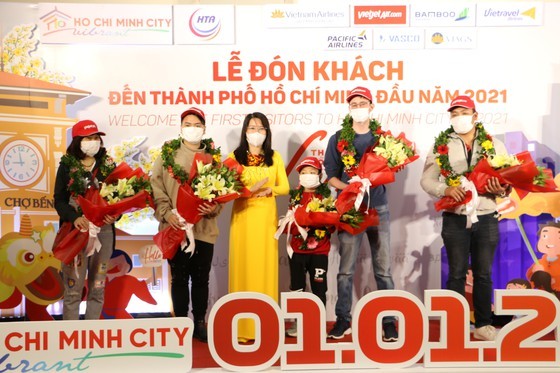 Director of the municipal Department of Tourism, Nguyen Thi Anh Hoa (C) offers flowers to first visitors to HCMC. (Photo: SGGP)