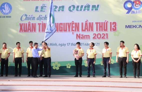 Head of the HCMC Party Committee's Mass Mobilization Commission Nguyen Huu Hiep (L) hands over a flag to students to kick off the campaign. (Photo: SGGP)