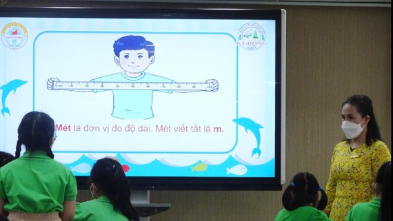 Giáo viên giới thiệu đơn vị đo độ dài mới là "mét" cho học sinh