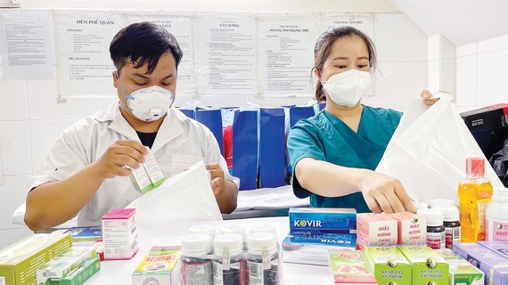 Để F0 yên tâm điều trị tại nhà: Cần đồng bộ nhiều giải pháp Nhân viên Trạm Y tế phường Nguyễn Cư Trinh, quận 1, TPHCM đang phân thuốc cung cấp bệnh nhân F0 tại địa phương. Ảnh: HOÀNG HÙNG