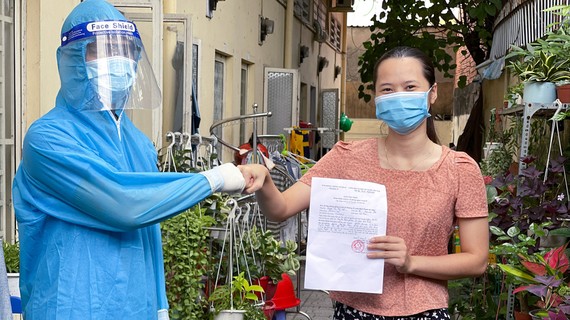 Cùng nhau vượt qua gian khó - Bài 3: Gượng dậy sau mất mát Đại diện Trạm y tế lưu động số 27 (phường 25, quận Bình Thạnh) cấp giấy chứng nhận hoàn thành cách ly y tế ngừa Covid-19 cho người dân tại khu căn hộ An Huy, đường Ung Văn Khiêm. Ảnh: HOÀNG HÙNG