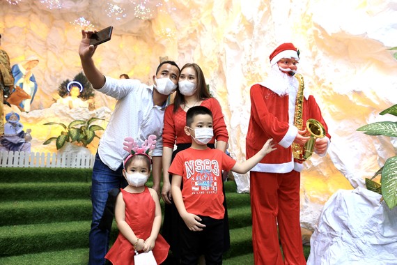 Người dân TPHCM vui đón Giáng sinh Một gia đình chụp ảnh lưu niệm bên hang đá ở nhà thờ giáo xứ Thị Nghè. Ảnh: DŨNG PHƯƠNG