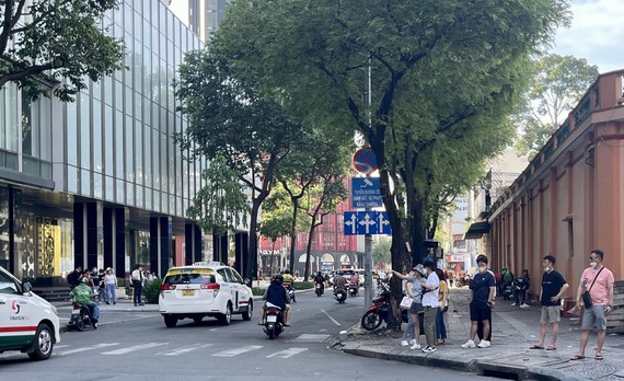 Khó đặt được taxi, xe công nghệ Các bạn trẻ và khách du lịch đón taxi phía ngoài cổng trung tâm thương mại ở TPHCM. Ảnh: HOÀNG HÙNG