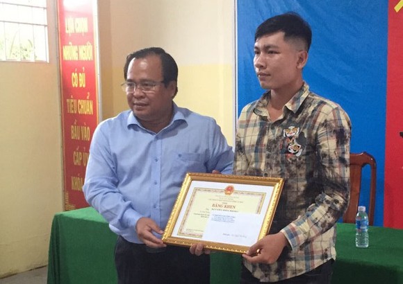 Phó Chủ tịch UBND tỉnh Cà Mau Nguyễn Minh Luân (trái) trao Bằng khen cho anh Nguyễn Hiền Phong
