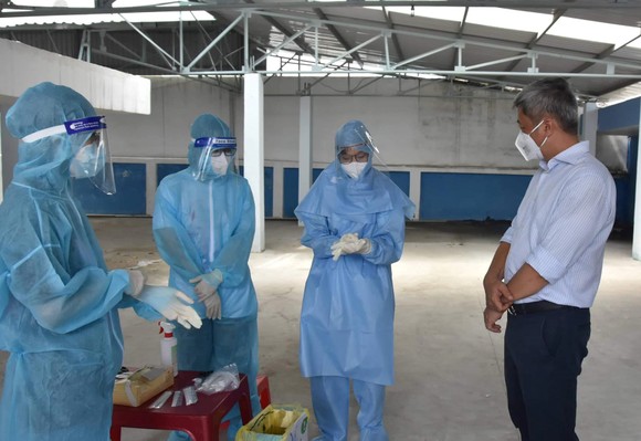 Thứ trưởng Bộ Y tế Nguyễn Trường Sơn thăm hỏi động viên nhân viên y tế lấy mẫu xét nghiệm cho người dân tại phường 25, quận Bình Thạnh.  Ảnh: KHÔI NGUYÊN