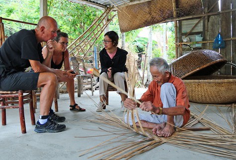Ông Vũ Văn Khá (làng Kim Bồng, xã Cẩm Kim, TP Hội An) biểu diễn nghề đan thúng chai cho khách nước ngoài thưởng lãm
