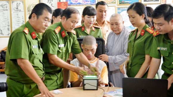 Cán bộ Đội Quản lý hành chính về trật tự xã hội Công an quận 12 làm thủ tục lấy vân tay cho em Phạm Minh Quân bị bệnh bại não tại cơ sở Mái ấm Minh Tâm