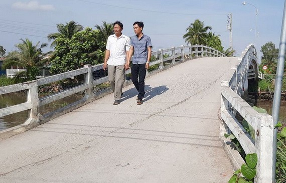 阮文俊（左）走在他捐出逾6000萬元來築的橋上。