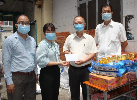 穗城會館理事長盧耀南(右二)和副理事長林海泉(右一)向坊領導移交支持防疫物資和現金。