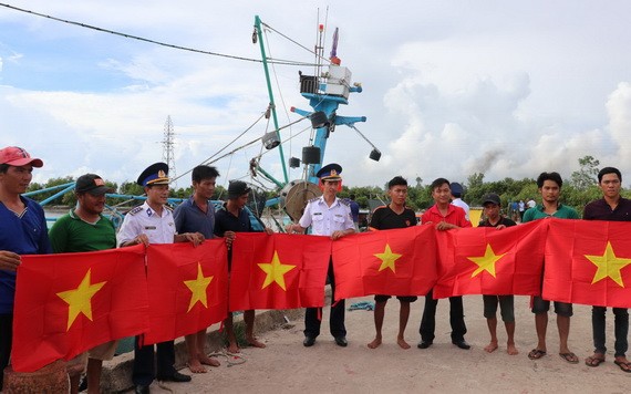 第四區海警司令部代表向堅江省安明縣漁民贈送國旗。（圖：V. Tôn）