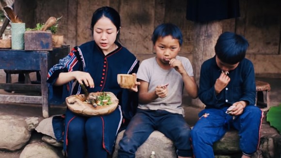 Vương Anh cùng trẻ em bản địa thưởng thức món bồ câu nướng vừa nấu tại Tủa Châu - Điện Biên  (Ảnh cắt từ clip)
