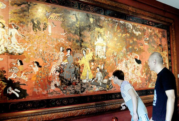 Khách tham quan xem tác phẩm sơn mài Vườn xuân Trung - Nam - Bắc  của danh họa Nguyễn Gia Trí. Ảnh: AN DUNG