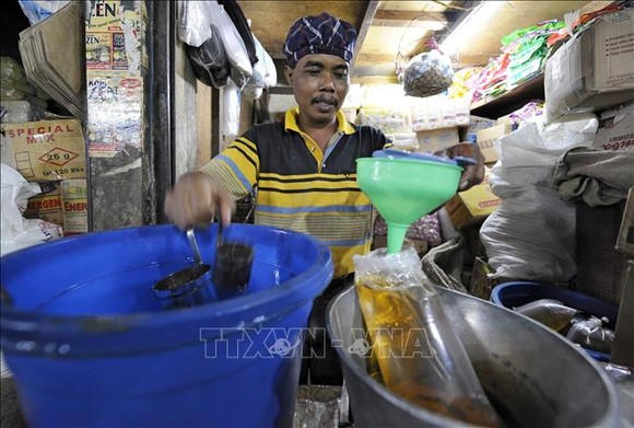 Người dân đong dầu ăn để bán tại một khu chợ ở Jakarta, Indonesia. Ảnh: AFP/TTXVN